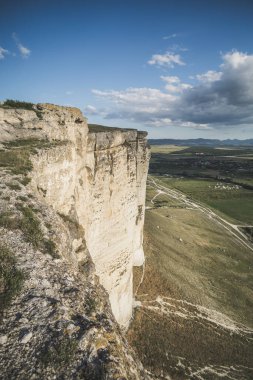 Bazalt 'ın dikey yüksek uçurumu ve çimlerle kaplanmış kumtaşı tepeleri ve dağları, mavi akşam gökyüzünü gösteriyor.