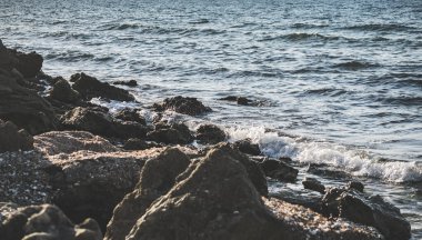 Sıcak bir yaz akşamında, Karadeniz 'in gel-git dalgaları kayalık bir kıyıya vurur ve tuzlu su ve köpük oluşturur.