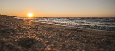 Karadeniz kıyısında ılık sörf dalgaları ve ılık yaz akşamıyla panoramik turuncu gün batımı
