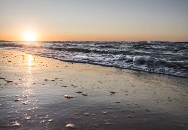 Sıcak bir yaz akşamında, ılık günbatımı ışığı ve parlak güneşle kıyıda Karadeniz 'in ılık deniz dalgaları.
