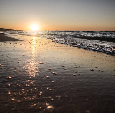Ilık ve parlak batan güneş, sıcak bir yaz akşamında Karadeniz 'in kırılan dalgasının ayna yüzeyine yansıyor.