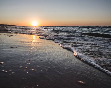 Karadeniz kıyısında sıcak gün batımı ve sahilde denizin ayna yüzeyi, akşamları dalgaların deniz dalgaları