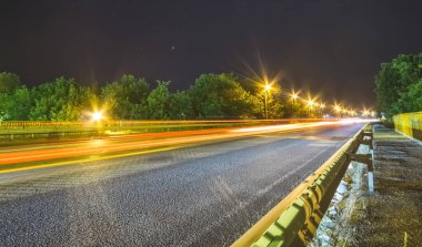 Köprü yolu karayolu, yıldızlı bir gecede uzun süre açık ve aydınlık fenerler, parlak kırmızı arabalar.