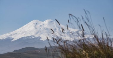 Dağlardaki otlar, Kafkaslar ve Elbrus Dağı 'nın görkemli arka planına karşı odak panoramik değildi. Sonbaharın güneşli bir günüydü.