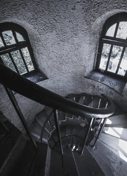 Old spiral staircase with railings in an ancient castle with old metal structures and dim lighting of old small windows on the side, in an ancient castle from old years