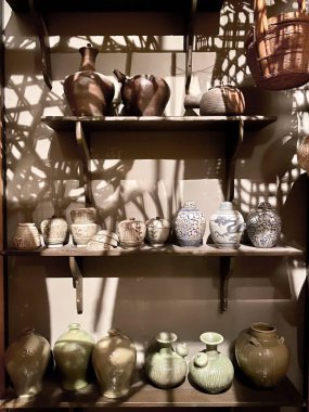Close-up of shelves of ceramic products with different patterns, textures on a dark background with shadows