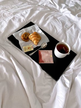 Breakfast in bed, cup of tea and croissants