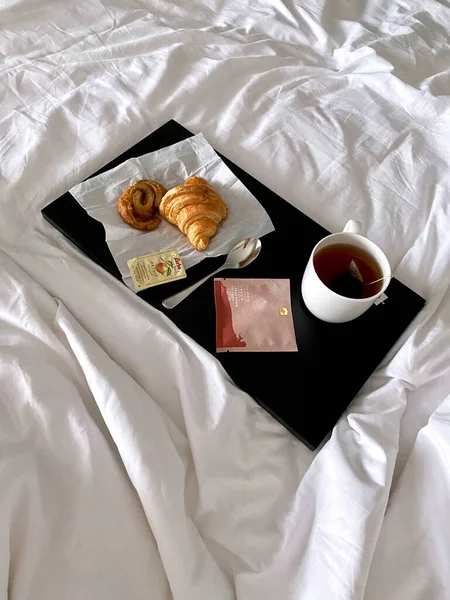 Breakfast in bed, cup of tea and croissants