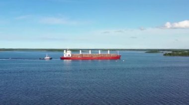 Bu, kereste yüklü büyük bir gemiye doğru uçarken çekilen bir drone görüntüsü, bir römorkör kereste gemisini yavaşlatıyor ve Pietarsaari (Jakobstad) limanına ulaşmadan önce onu durduruyor..