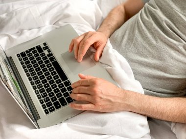 Middle aged adult man using laptop at home In bed vibes white bedsheets Alone Early morning working. freelancer, freelance job, using technology, using social media, watching movie, checking news