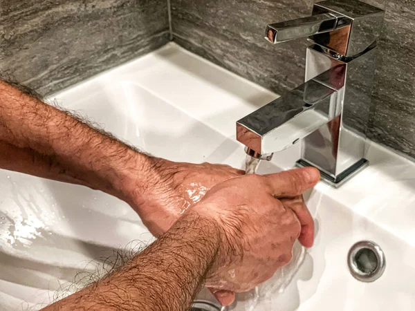 Personal hygiene: man is washing hands with soap properly at home.