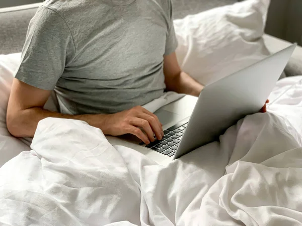 Middle aged adult man using laptop at home In bed vibes white bedsheets Alone Early morning working. freelancer, freelance job, using technology, using social media, watching movie, checking news