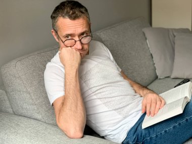 Küçük bir dairede kendini izole etmek, zihinsel olarak yanmış bir adam evdeki koltukta oturup kitap okumaktan sıkılmış, yalnızlık hisseden, kırık ilişki, depresyon, akıl sağlığı...