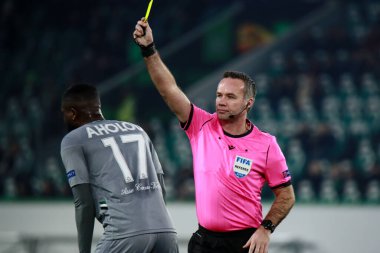 Wolfsburg, Almanya, 12 Aralık 2019: İngiliz hakem Paul Tierney UEFA Avrupa Ligi maçı sırasında futbolcu Jean-Eudes Aholou 'ya sarı kart gösterdi