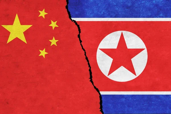 China and North Korea painted flags on a wall with a crack. China and North Korea relations
