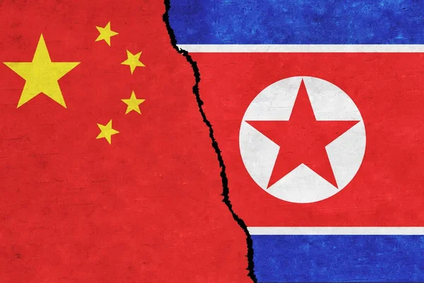 China and North Korea painted flags on a wall with a crack. China and North Korea relations