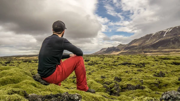 İzlanda 'nın kuzeyindeki dağlarda uzanan lav tarlalarını izleyen bir adam..