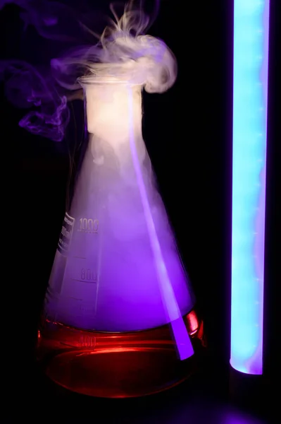 Strong chemical reaction with a lot smoke and vapors inside Erlenmeyer flask. School chemical experiment Vessel with a red liquid and purple smoke. Background picture. High quality photo