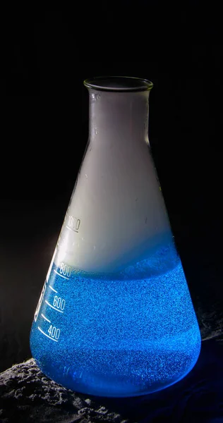 Erlenmeyer flask with a blue liquid and smoke which has been created by a chemical reaction. Background picture. . High quality photo