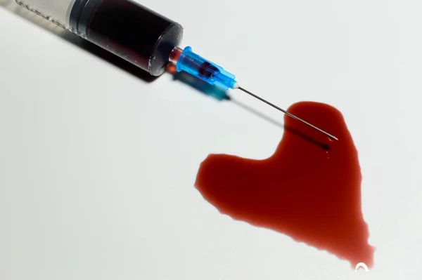 針の端から血が滴り落ちる医療用注射器 心臓シンボルを作成します 高品質の写真 — ストック写真