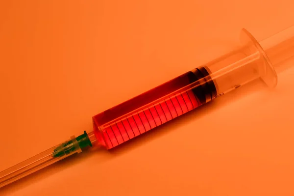 オレンジ色の背景に赤い血を持つ医療用注射器 コロナウイルスと天然痘に対する血液検査 治療だ そうだ 高品質の写真 — ストック写真