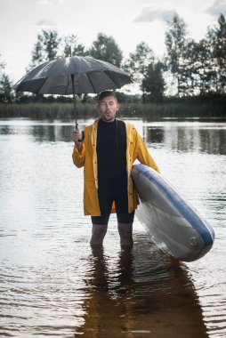 Şemsiyeli bir sörfçü suda duruyor, kötü hava kavramı.