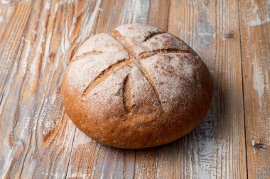 Ahşap masadaki kesiklerle süslenmiş iştah açıcı yuvarlak ekmek, metin alanlı rustik fotoğraf, etrafta dikenler