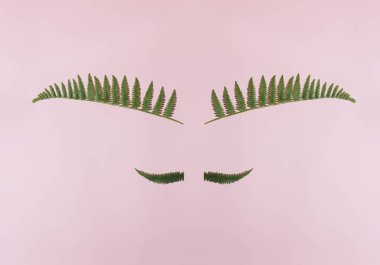 Creative concept of face made of natural green leaves. Flat lay.