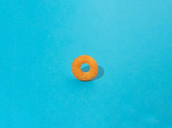 Yellow ring of cookie on blue background. Unique flat lay concept.