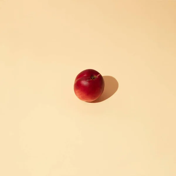 Fresh nectarine against pastel beige background. Minimal fall fruit layout.