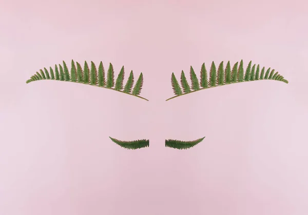 Creative concept of face made of natural green leaves. Flat lay.