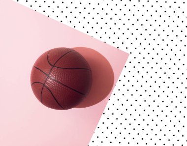 Basket ball on pastel pink and white  background with black dots . Minimal flat lay concept. Sports style.