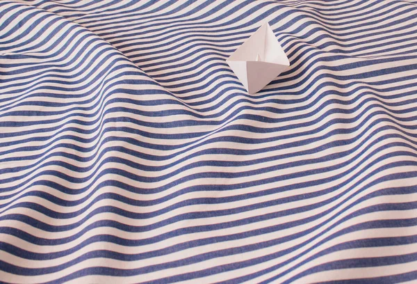 White paper boat on the wather surface. Sumeer seascape with waves. Vacation minimal concept