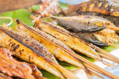 Şef müşteriler için ızgara yemek hazırlar, balık da dahil.,