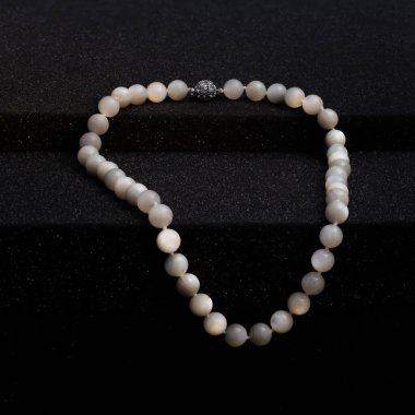 Woman jewelry elegant pearl necklace on black background.