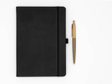 Yanında altın kalem olan kaliteli siyah deri defter, beyaz arka planda izole edilmiş.