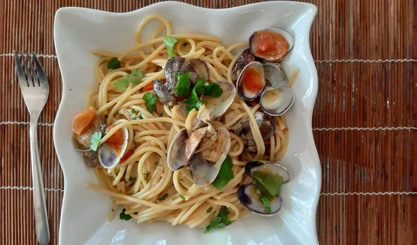 İstiridyeli spagetti, kiraz domatesli ve maydanozlu, beyaz kasede servis edilen makarna.