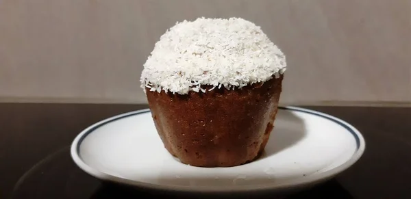 Siyah arka planda seramik tabakta küçük hindistan cevizli kek.