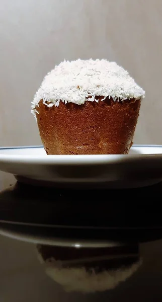 Siyah arka planda seramik tabakta küçük hindistan cevizli kek.