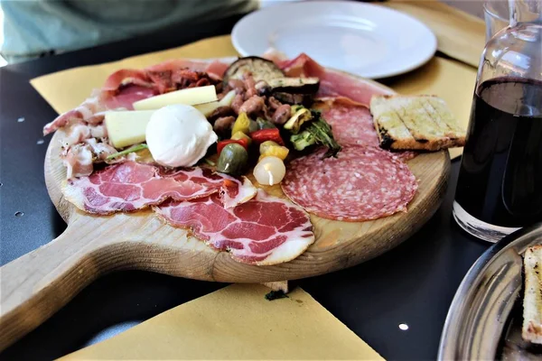 Bir tabak soğuk et, peynir ve sebze, bruschetta, tahtada kırmızı şarap, siyah masa.