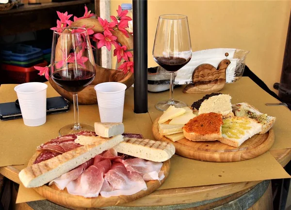 İtalyan aperatifi, lezzetli bir tabak İtalyan, yaşlanmış ve taze peynir, pişirilmiş etler, jambon, bruschetta ve pizza iki bardak İtalyan kırmızı şarabına eşlik etmek üzere ahşap tepsiye konmuş.