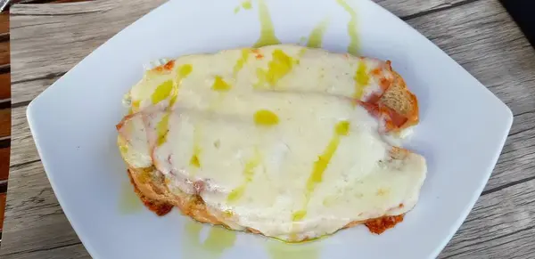 İtalyan aperatifi Crostone yağlı jambon ve ahşap masada beyaz tabakta mozzarella.
