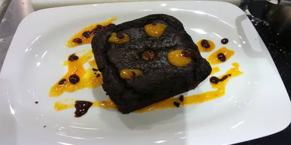 Beyaz tabakta mango soslu çikolatalı tatlı, fırında vejetaryen tatlı.