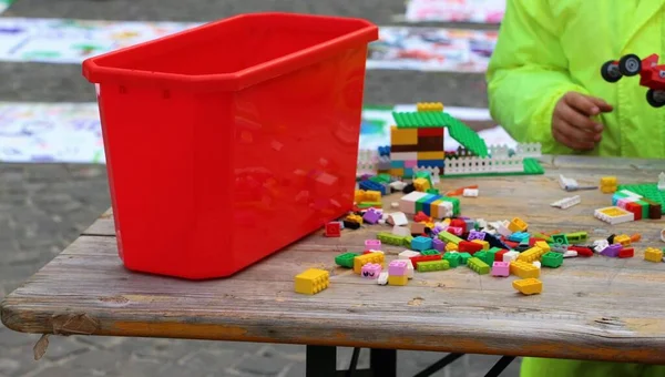 Oynamak ve oynamak için nesneler yapmak için küçük renkli plastik parçalarla dolu kırmızı kutu, oyuncak yapılarıyla oynayan çocuk 