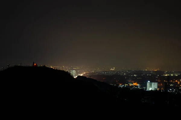 Several people were camping on the hill, with the city lights all around.