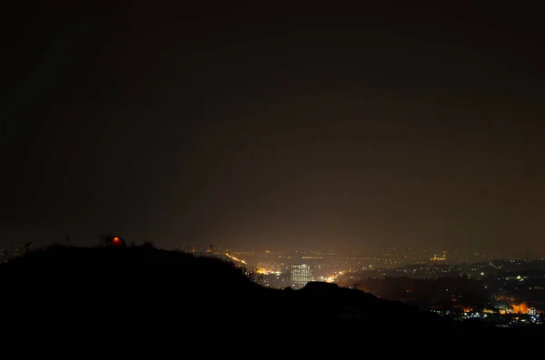 Several people were camping on the hill, with the city lights all around.
