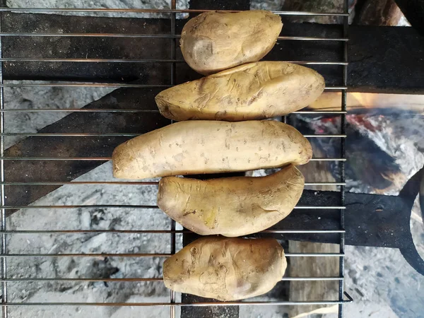 Cilembu sweet potato being heated in hot coals. It has its own uniqueness, because when it is roasted it will release a sweet liquid. That\'s why this yam often called \