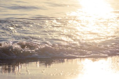 Sunlit Waves Crashing onto The Beach at Daybreak