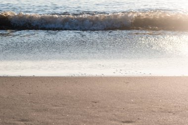 Sunlit Waves Crashing onto The Beach at Daybreak