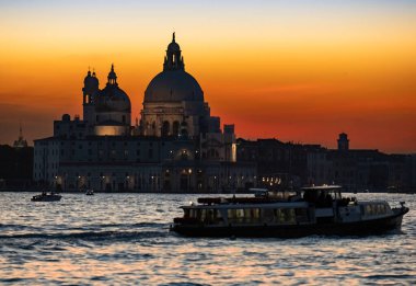 Venice, Santa Maria della Salute Church at sunset 2021, with boats and Vaporetto seabus in the lagoon canals. High quality photo.